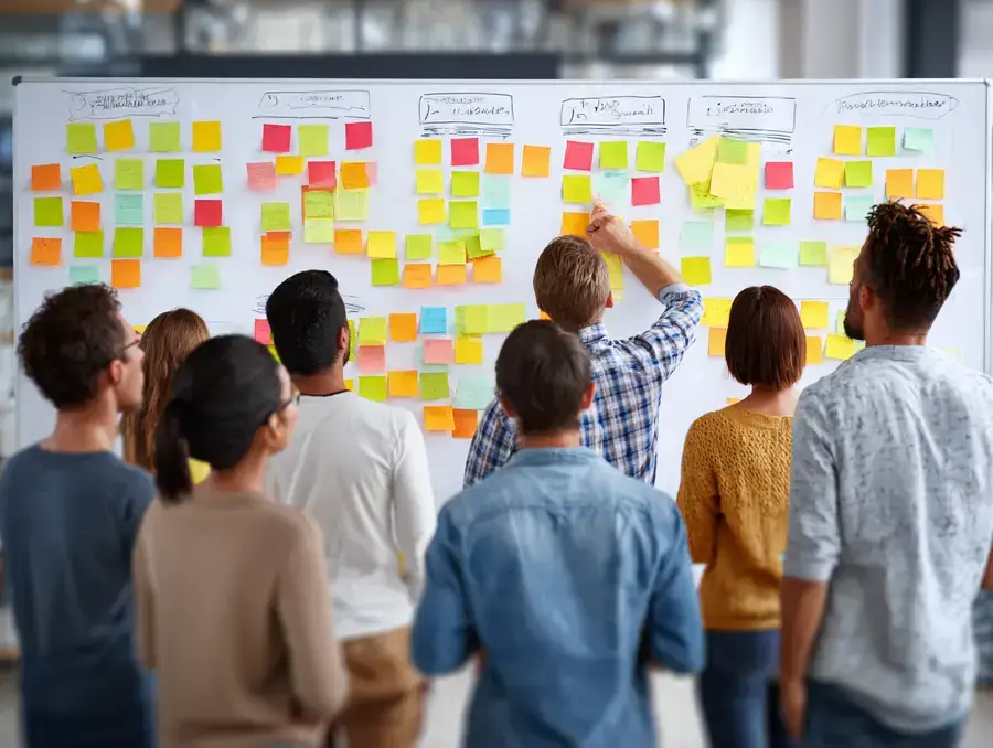 Kernmerkmale des partizipativen Führungsstils: Team arbeitet an Whiteboard, Ideen und Informationen werden sichtbar geteilt.